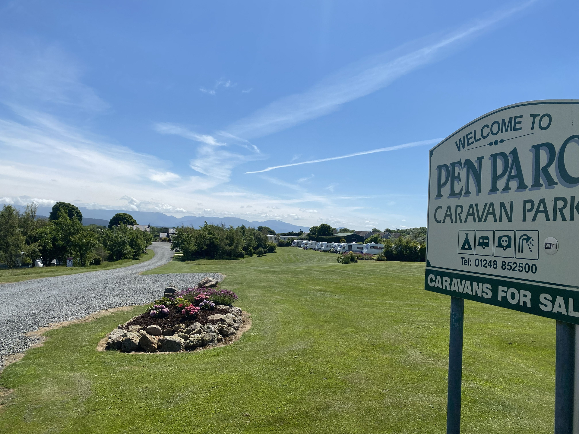 Pen Parc Caravan Park entrance sign with caravans and Snowdonia mountains in the background